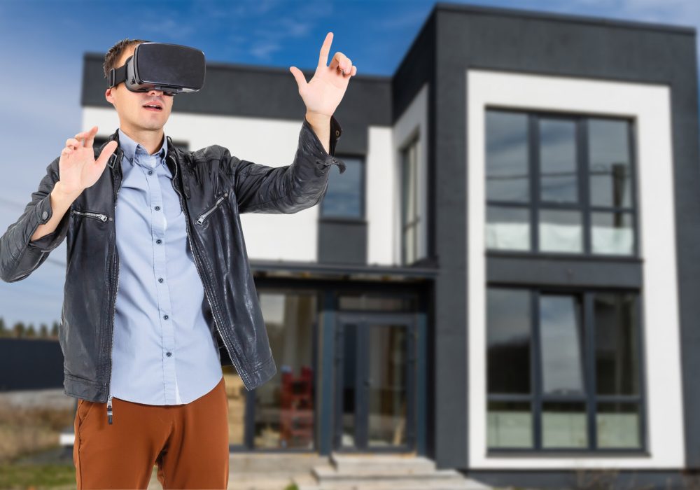 Cheerful man in virtual glasses in front of new house.